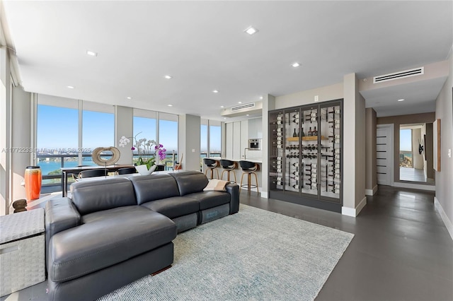 living room with recessed lighting, visible vents, a water view, baseboards, and expansive windows