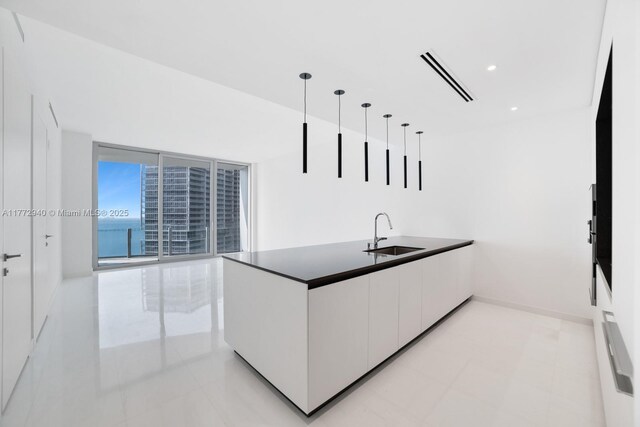 kitchen featuring a sink, a peninsula, white cabinets, dark countertops, and modern cabinets