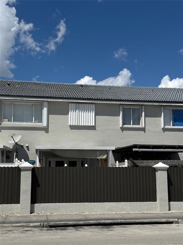 exterior space featuring a fenced front yard, stucco siding, and a tile roof