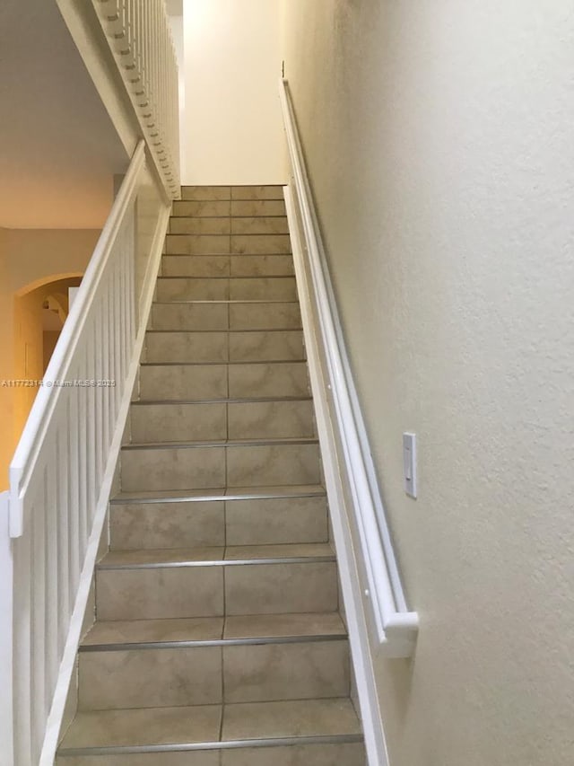 staircase featuring arched walkways