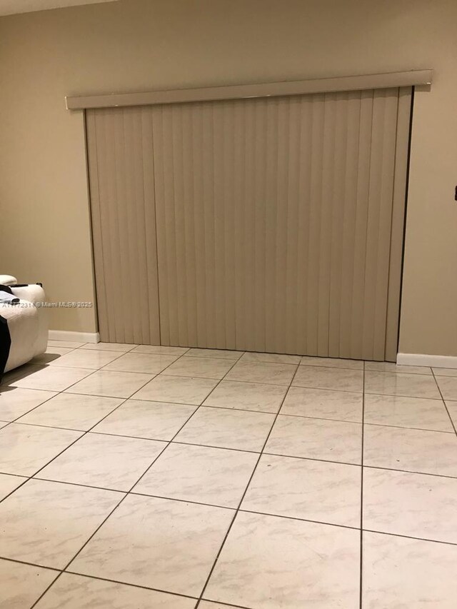 unfurnished room with baseboards and light tile patterned floors