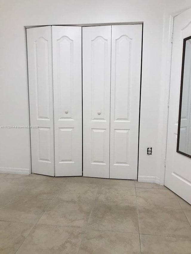 unfurnished bedroom with light tile patterned floors, baseboards, and a closet