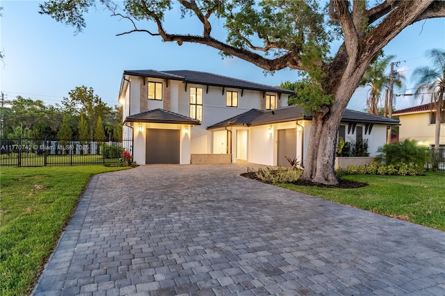 view of front of home featuring a front yard, decorative driveway, fence, and an attached garage