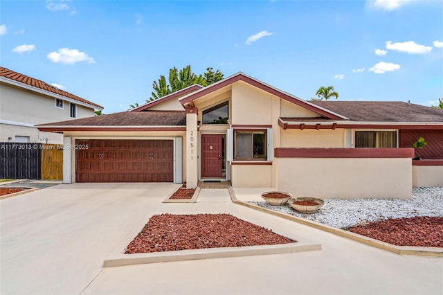 mid-century modern home with fence, roof with shingles, a garage, stucco siding, and concrete driveway