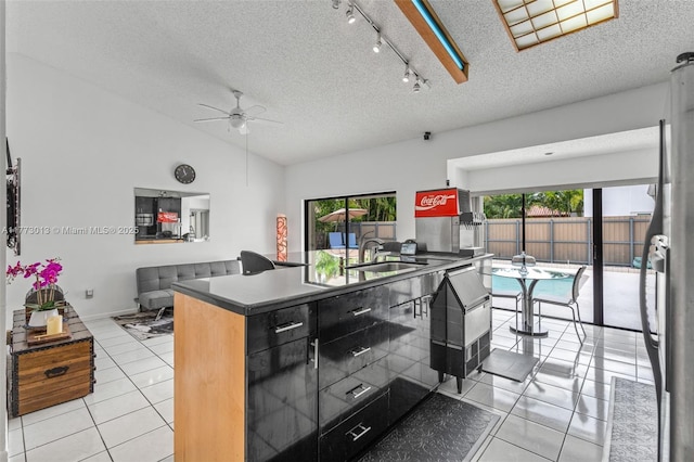 kitchen featuring light tile patterned flooring, ceiling fan, a sink, and a textured ceiling