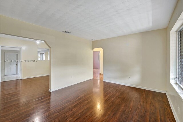 2331 NW 92nd St, Miami, FL 33147 - empty room with baseboards, visible vents, wood finished floors, and arched walkways