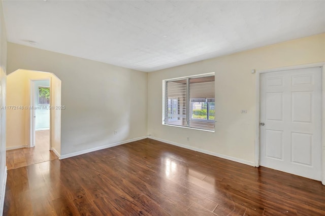2331 NW 92nd St, Miami, FL 33147 - empty room with plenty of natural light, baseboards, wood finished floors, and arched walkways