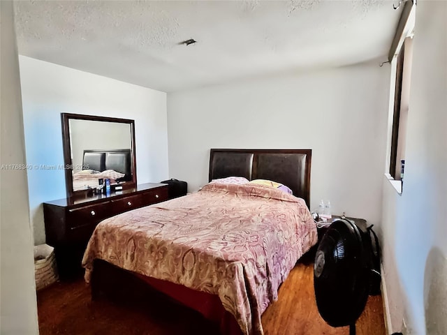 bedroom featuring a textured ceiling and wood finished floors
