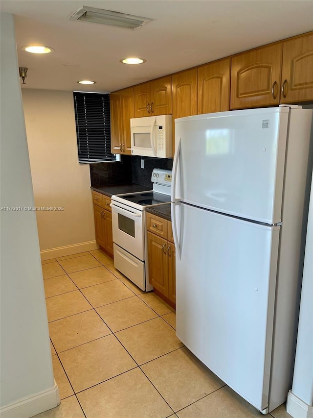 2400 SW 3rd Ave Unit 605, Miami, FL 33129 - kitchen featuring brown cabinets, dark countertops, light tile patterned floors, white appliances, and visible vents