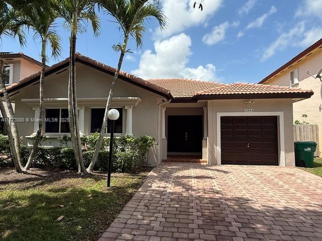 mediterranean / spanish-style home with a tile roof, a garage, decorative driveway, and stucco siding