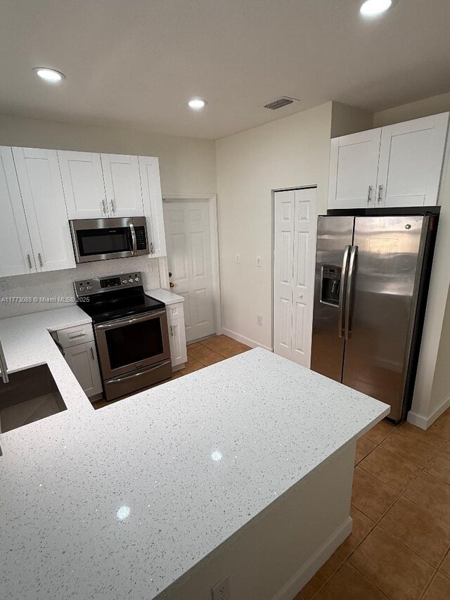 kitchen with a sink, visible vents, white cabinets, light stone countertops, and appliances with stainless steel finishes