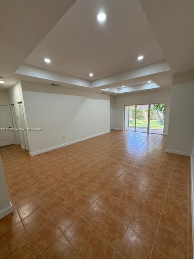 spare room with tile patterned flooring, a tray ceiling, baseboards, and recessed lighting