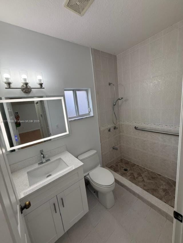 bathroom with a stall shower, toilet, vanity, a textured ceiling, and visible vents