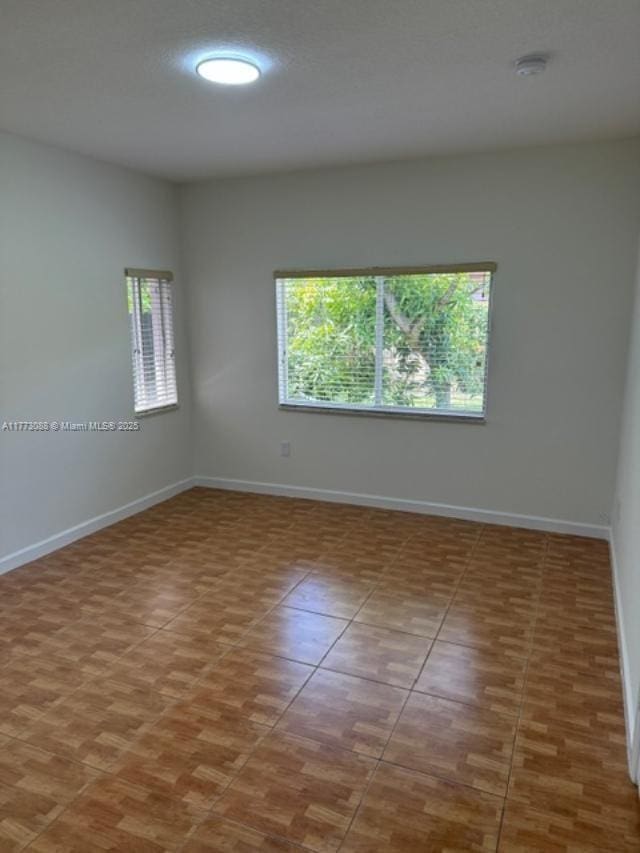 tiled spare room featuring baseboards