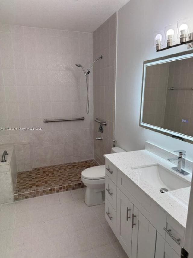 full bathroom featuring toilet, vanity, and a tile shower