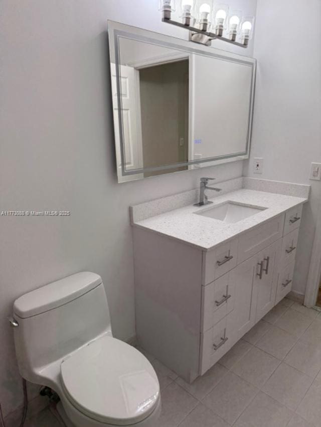 bathroom with an inviting chandelier, toilet, vanity, and tile patterned flooring