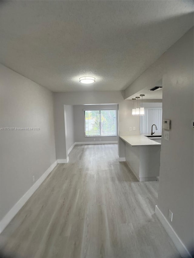 6990 NW 17th St, Margate, FL 33063 - unfurnished living room featuring a sink, baseboards, light wood finished floors, and a textured ceiling