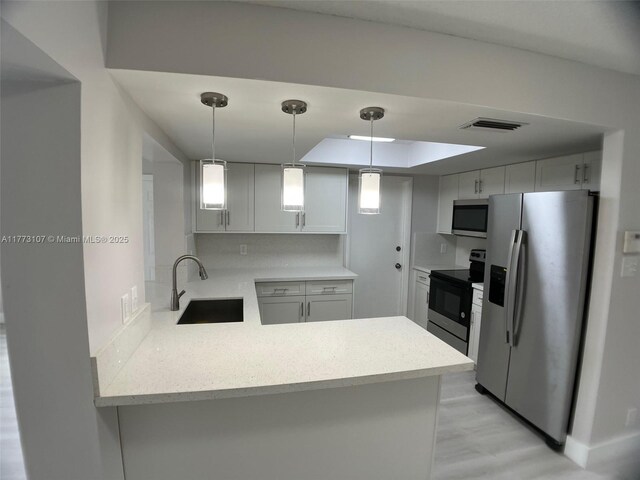 6990 NW 17th St, Margate, FL 33063 - kitchen with a sink, a peninsula, stainless steel appliances, visible vents, and decorative light fixtures