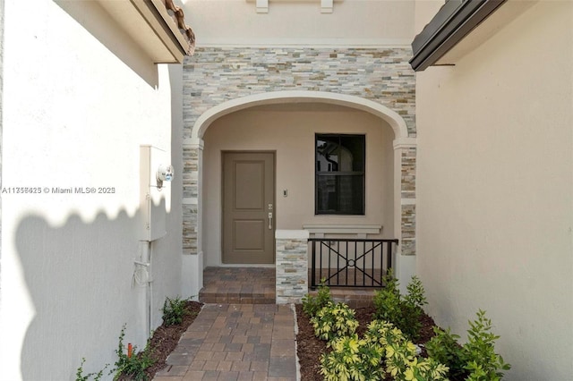 property entrance featuring stucco siding and stone siding