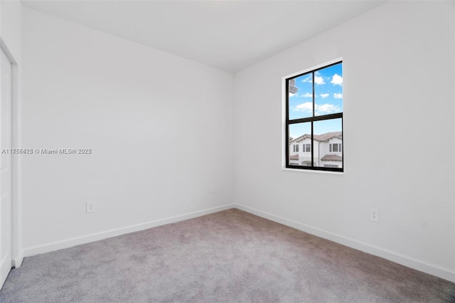 spare room with baseboards and carpet floors