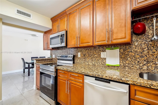 1849 S Ocean Dr Unit 711, Hallandale Beach, FL 33009 - kitchen featuring appliances with stainless steel finishes, tasteful backsplash, brown cabinetry, and dark stone countertops