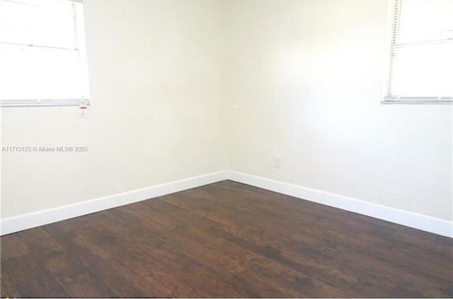 unfurnished room featuring baseboards and dark wood-style floors