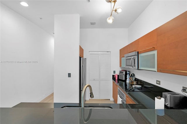 244 Biscayne Blvd Unit 206, Miami, FL 33132 - kitchen featuring stainless steel appliances, dark countertops, brown cabinets, and a sink