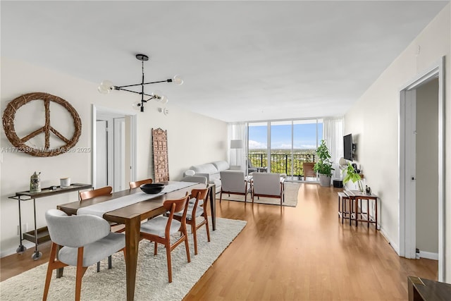 dining area with floor to ceiling windows, light wood finished floors, and a notable chandelier