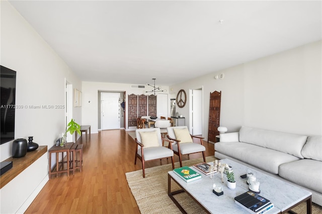 living room with light wood-style floors, baseboards, a chandelier, and visible vents