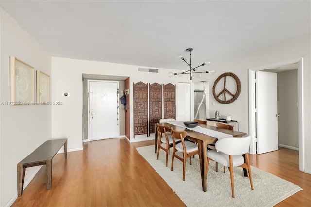 dining area with visible vents, baseboards, a notable chandelier, and light wood-type flooring