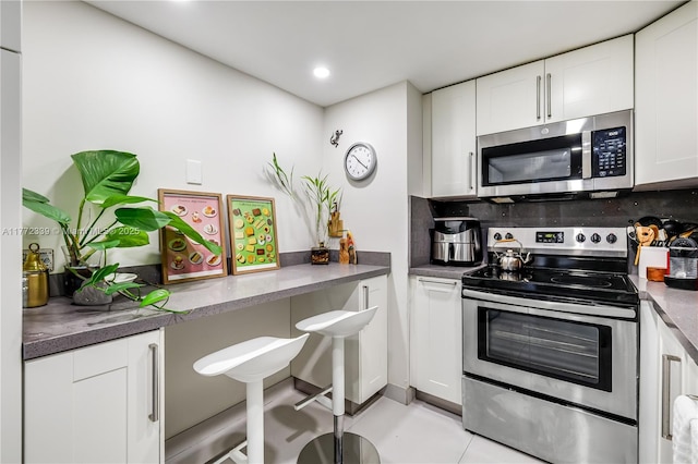 kitchen with dark countertops, recessed lighting, white cabinetry, tasteful backsplash, and stainless steel appliances