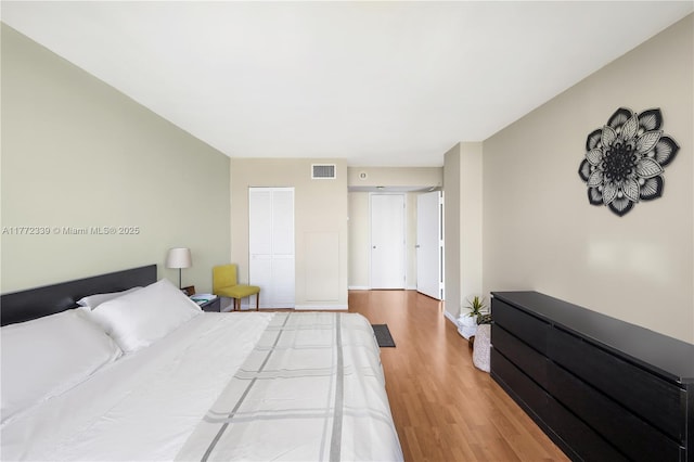 bedroom featuring baseboards, visible vents, and wood finished floors