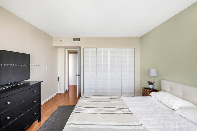 bedroom featuring baseboards, a closet, light wood-type flooring, and visible vents