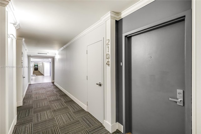 hall with crown molding, baseboards, and dark colored carpet