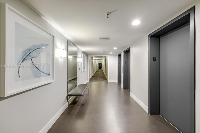 hall with recessed lighting, baseboards, elevator, and visible vents