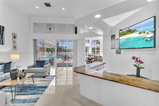 living area featuring light tile patterned floors, recessed lighting, a towering ceiling, and visible vents