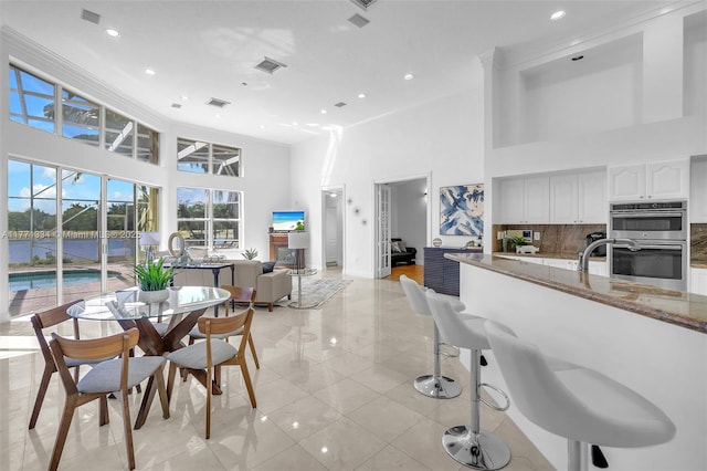 dining room featuring visible vents, a towering ceiling, and recessed lighting