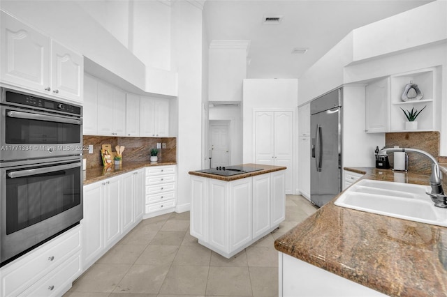 kitchen featuring open shelves, a center island, a sink, visible vents, and appliances with stainless steel finishes
