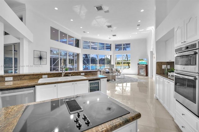 kitchen with white cabinets, a sink, wine cooler, and appliances with stainless steel finishes