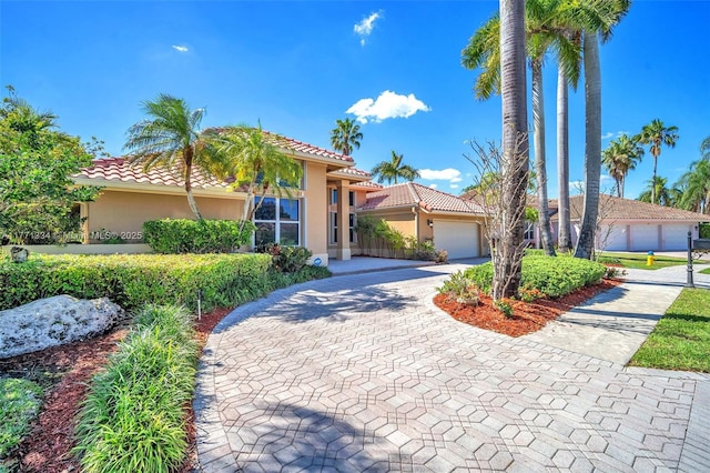 mediterranean / spanish home with driveway, stucco siding, a tile roof, and an attached garage