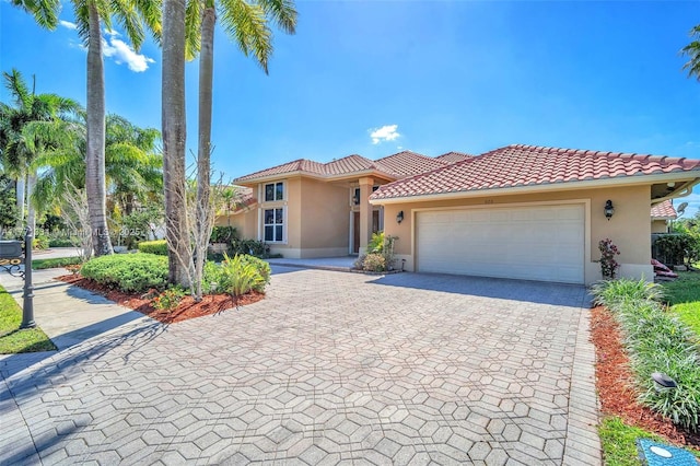 mediterranean / spanish-style house featuring decorative driveway, stucco siding, a tiled roof, and a garage