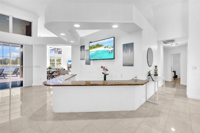 bar with baseboards, visible vents, a towering ceiling, and recessed lighting