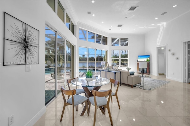 dining area with a towering ceiling, crown molding, baseboards, and visible vents