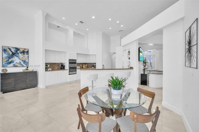dining space featuring a towering ceiling, recessed lighting, light tile patterned flooring, and visible vents