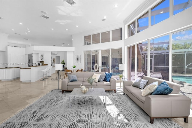 living area featuring a towering ceiling, recessed lighting, and visible vents