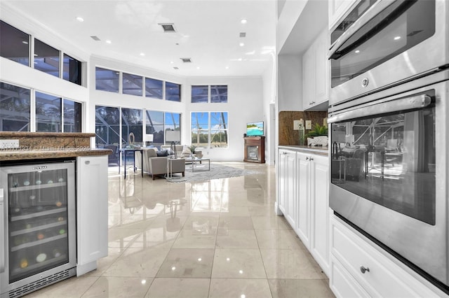 kitchen featuring white cabinetry, visible vents, wine cooler, and stainless steel oven