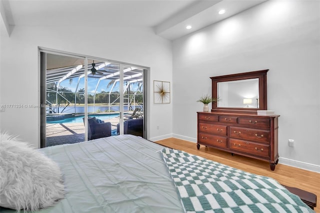 bedroom featuring wood finished floors, access to outside, lofted ceiling, a sunroom, and baseboards