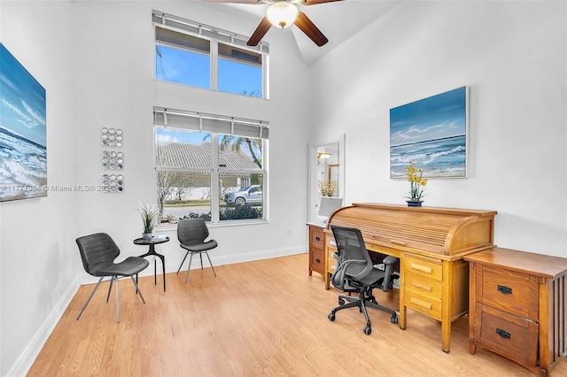 home office featuring baseboards, ceiling fan, high vaulted ceiling, and light wood-type flooring