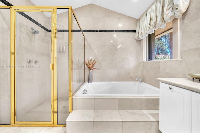 bathroom featuring a garden tub, a stall shower, tile walls, and vaulted ceiling