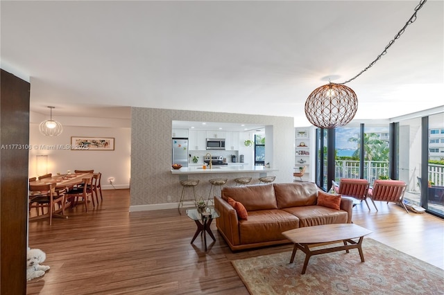 living area featuring wallpapered walls, baseboards, a chandelier, and wood finished floors